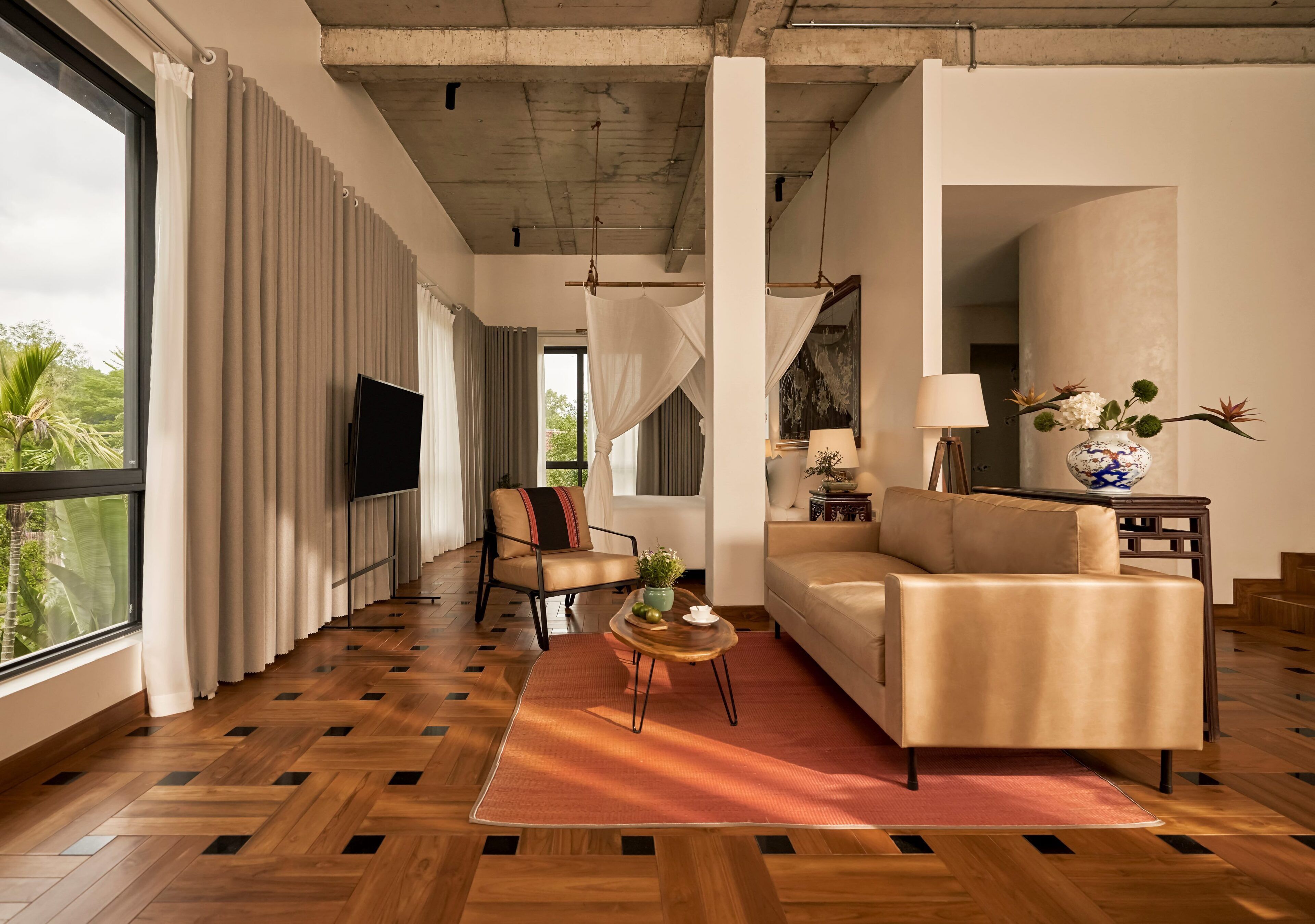 A modern living room with a sofa, armchair, and a TV on a wooden floor.