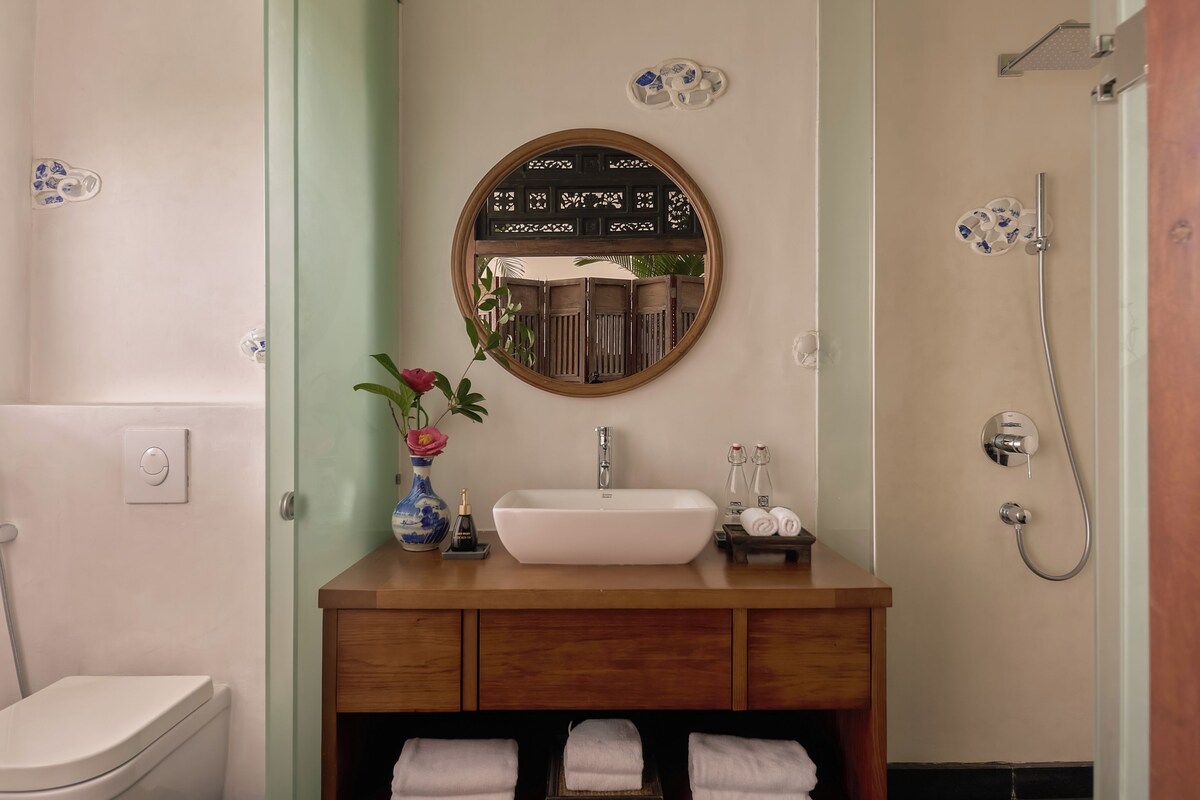 A bathroom with a white sink, a mirror, a shower, and a toilet.