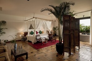 Una camera da letto con un letto a baldacchino, pavimento in legno e un'ampia pianta in vaso.