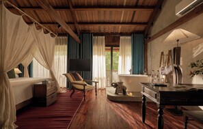 A room with a bed, a chair, a table, a bathtub, and a television. - Anhill Boutique (Hue)
