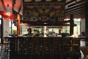 A bar area with a tiled backsplash, wooden stools, and a decorative ceiling mural. - Anhill Boutique (Hue)