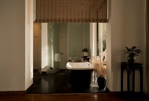 A modern bathroom with a freestanding bathtub, a glass shower enclosure, and a potted plant.