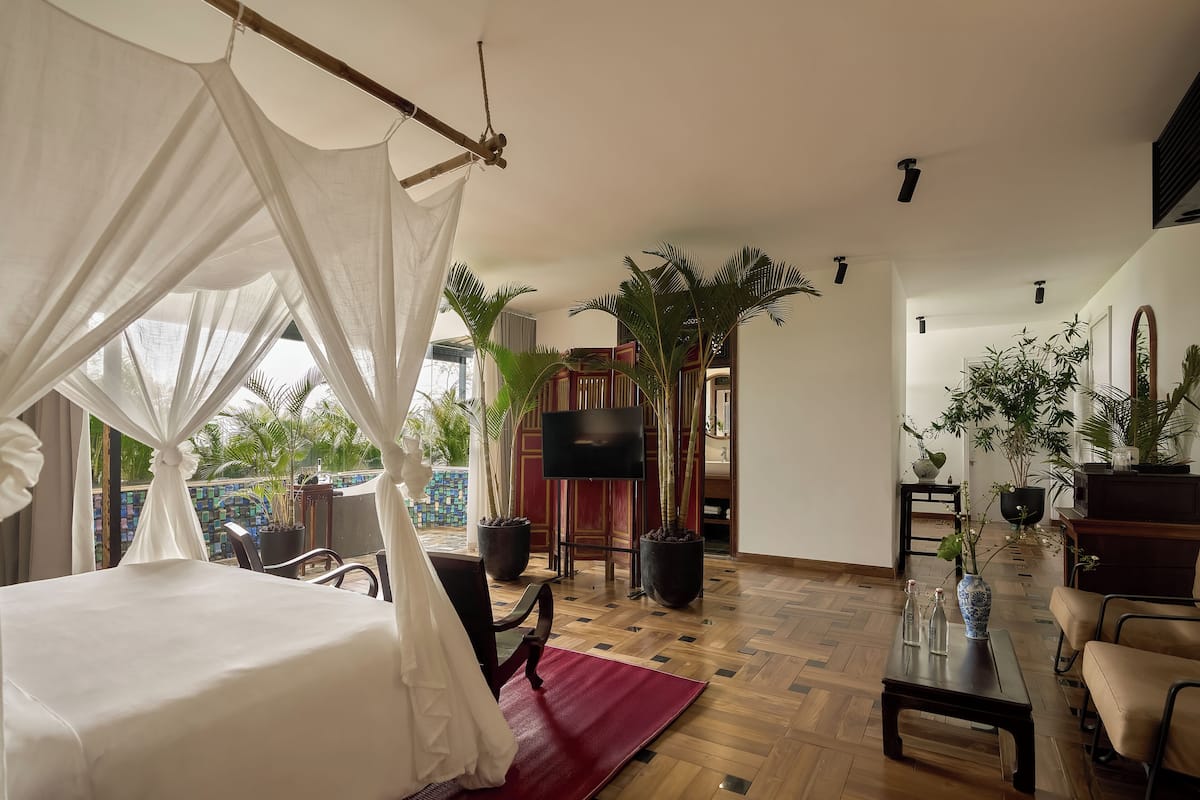 Una habitación con cama, televisión y plantas en macetas.