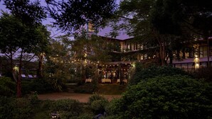 A courtyard with a dining area, surrounded by lush greenery and trees. - Anhill Boutique (Hue)