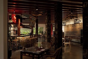 A restaurant with wooden furniture, a bar area, and a wall of wine bottles.