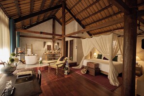 A spacious bedroom with a wooden ceiling, a large bed with a canopy, a bedside table, and a nightstand. - Anhill Boutique (Hue)