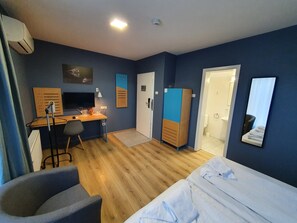A hotel room with a bed, a desk, a chair, a wardrobe, and a bathroom door. - Urban Point (Sfantu Gheorghe)