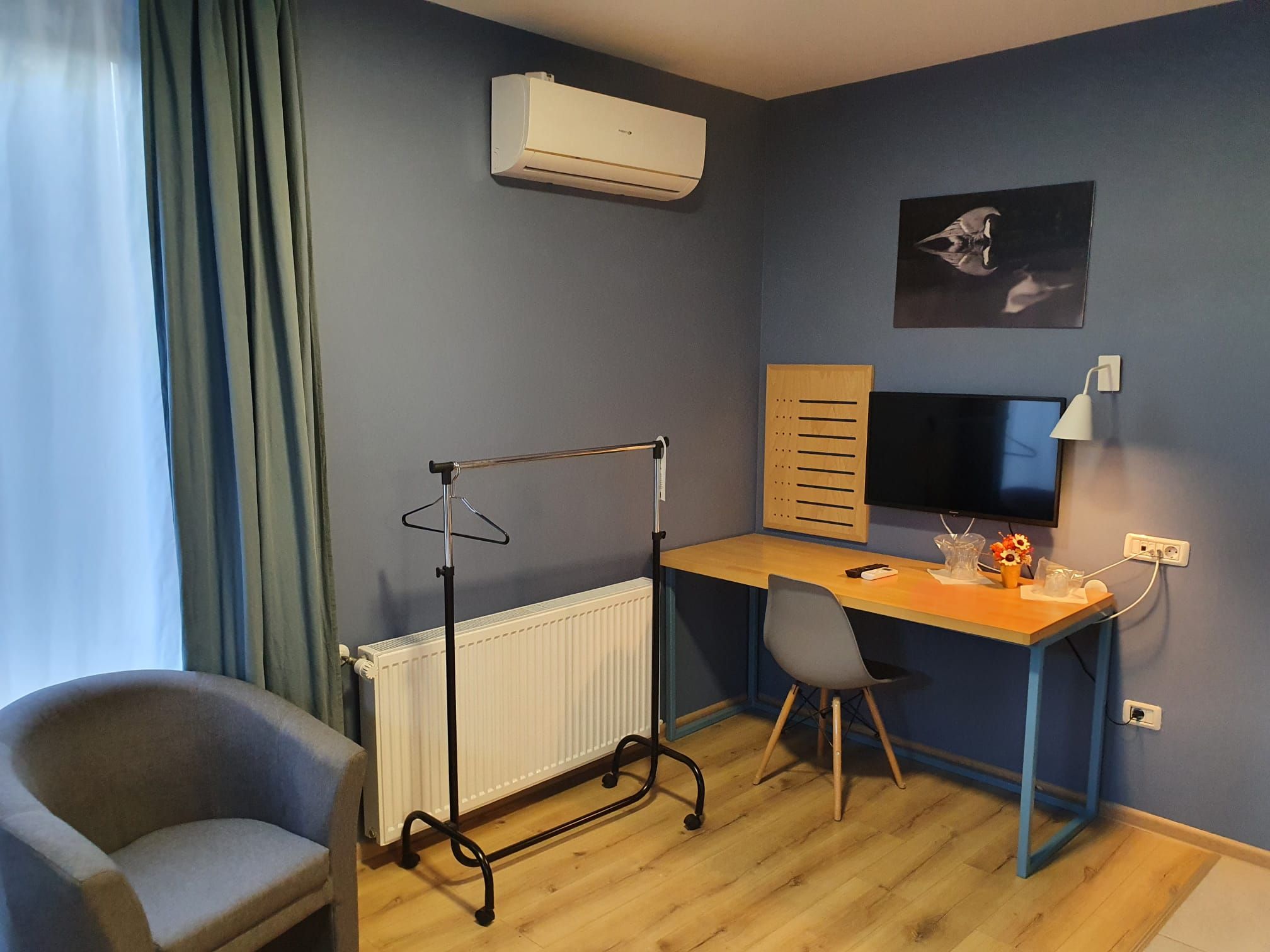 A room with a desk, chair, radiator, and an air conditioning unit.