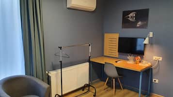 A room with a desk, chair, radiator, and an air conditioning unit.