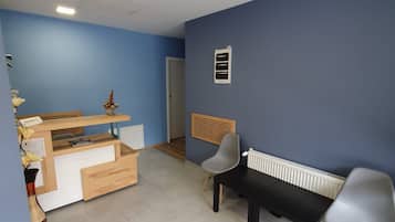 A room with a blue wall, a wooden desk, a black bench, and a radiator.