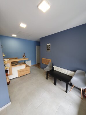 Une pièce avec un mur bleu, un bureau en bois, un banc noir et un radiateur.