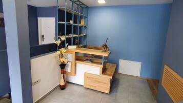 A reception area with a desk, shelving, a chair, and a potted plant.