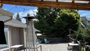A wooden deck with a grill, outdoor furniture, and string lights. - Beautiful Farm Style House (Eugene)