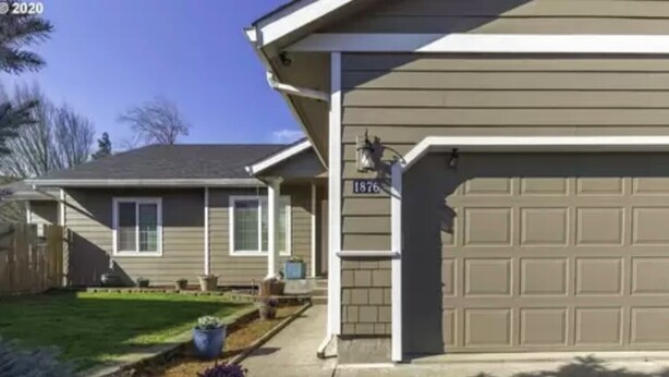 A residential house with a garage, numbered 1876, and a well-maintained lawn with potted plants. - Beautiful Farm Style House (Eugene)