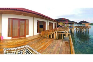 A waterfront property with wooden deck, overwater bungalows, and a covered area with a view of the water. - SBS Resort by Zuzu (Galang)