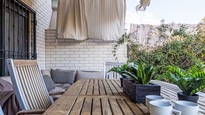 Ein Holztisch mit Stühlen, einem Sofa und Blumentöpfen.