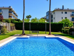 A swimming pool with a clear blue water surface, surrounded by a well-maintained lawn and a hedge. - Beautiful apartment for 4 people with A/C, pool, WIFI, TV and balcony (Sant Carles De La Ràpita)