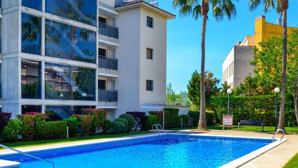 Ein Swimmingpool mit klarem, blauem Wasser, umgeben von einer gefliesten Terrasse und einem gepflegten Rasen.