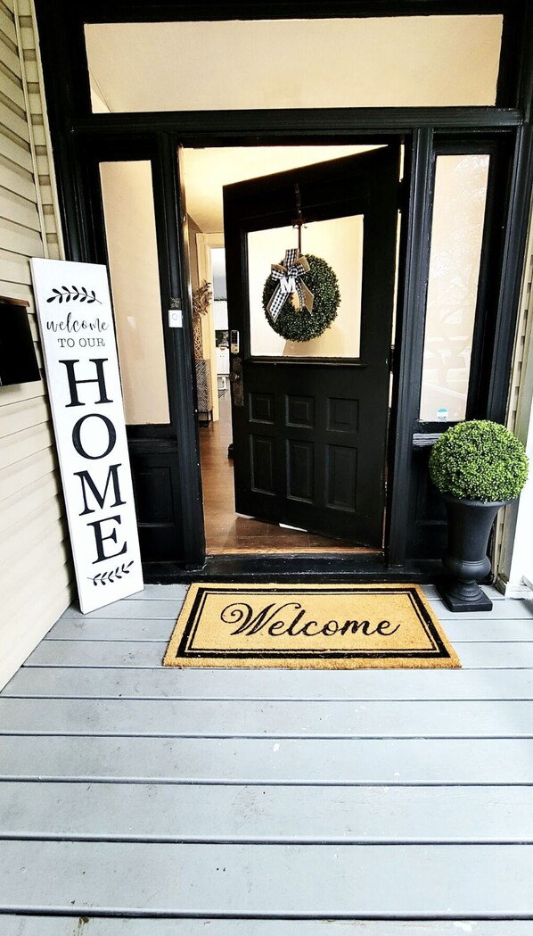 A front door with a 'Welcome' mat and a 'Home' sign.