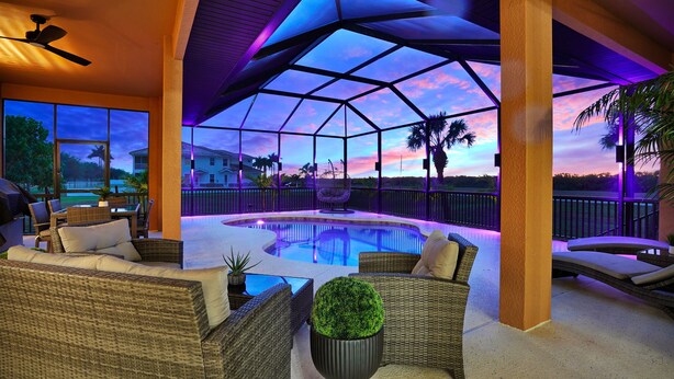Un espacio al aire libre techado con piscina, mobiliario de mimbre y vistas a la puesta de sol.