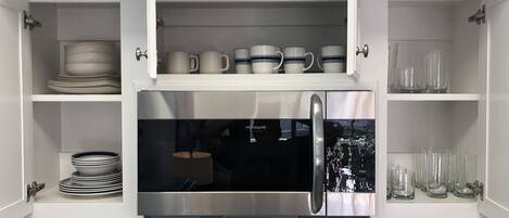 Una cucina con mobili bianchi, un frigorifero in acciaio inossidabile e una parete piastrellata.