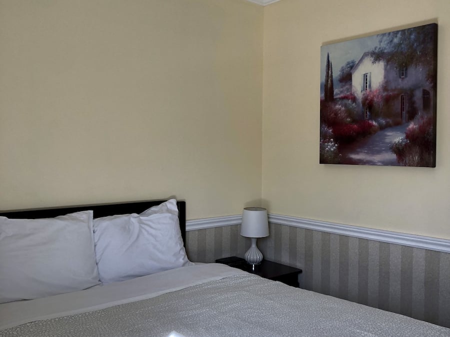 A hotel room with a bed, a nightstand, a lamp, and a painting on the wall.
