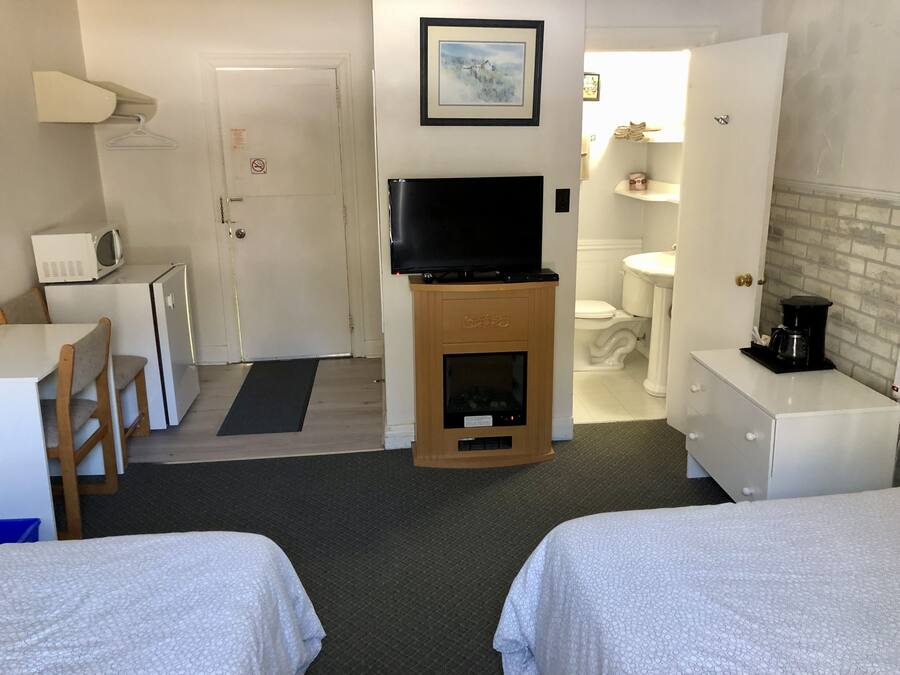 A hotel room with two beds, a TV, a microwave, a small kitchenette, and a bathroom.