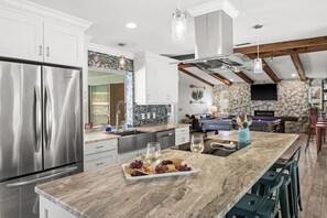 A modern kitchen with stainless steel appliances, a marble island, and a stone accent wall.