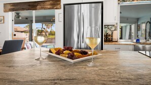 A kitchen with a stainless steel refrigerator, a marble countertop, and a glass of white wine. - Beautiful Dog Friendly Home with Screened-in Heated Pool, Game Room/Bar (Cape Coral)