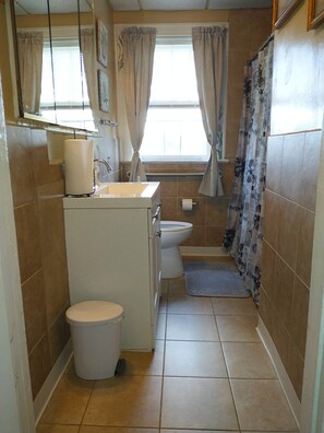 Bathroom features a toilet, sink, and shower area with a floral curtain.