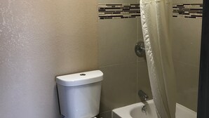 Un baño con inodoro, bañera y cortina de ducha.