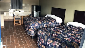 Habitación de hotel con dos camas, un escritorio pequeño con una silla, un lavamanos y un espejo.