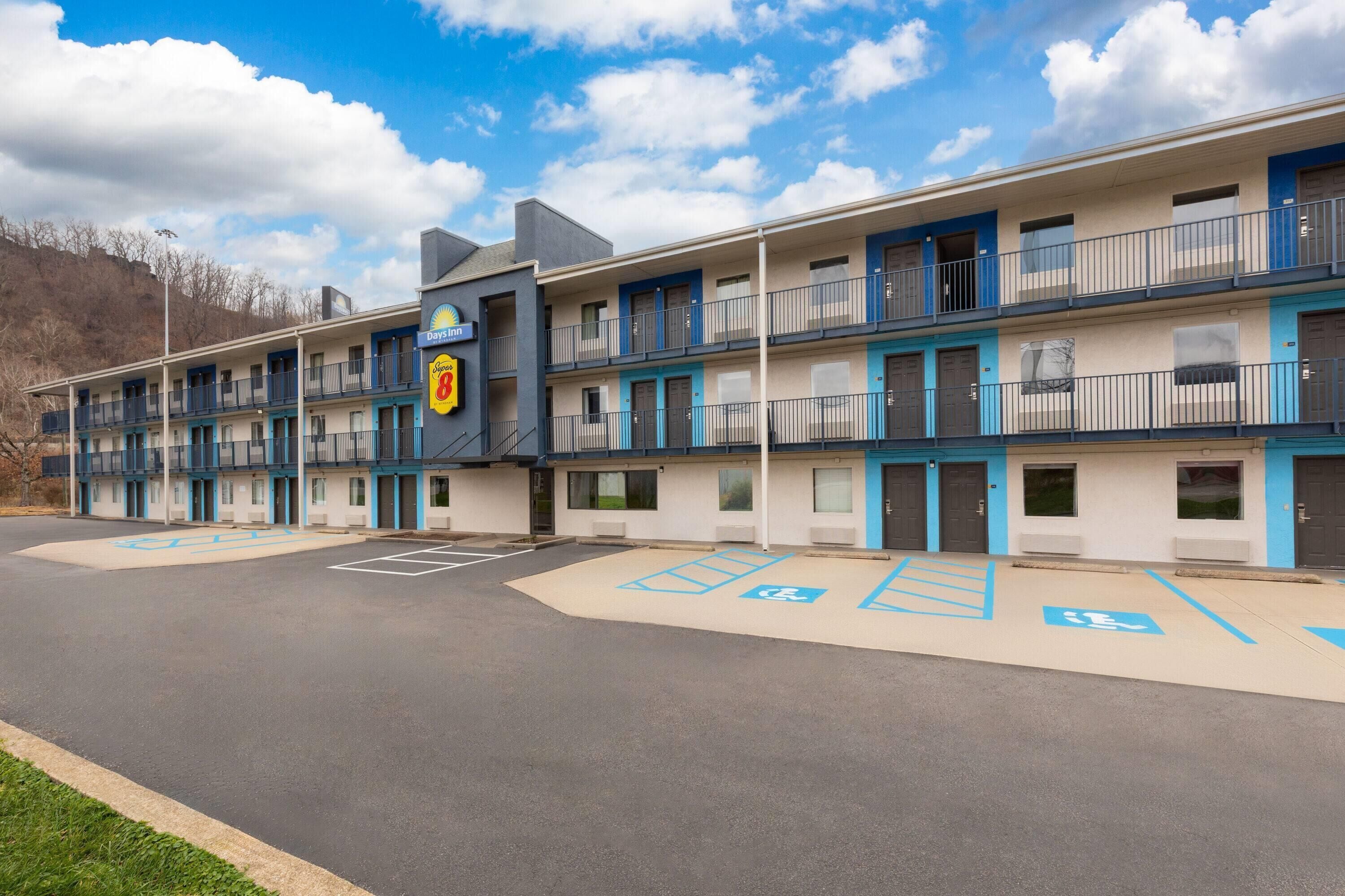 A motel with a two-story structure, multiple balconies, and designated parking spaces including handicapped spots.