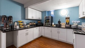 A modern kitchen with white cabinets, a black countertop, and a blue wall.