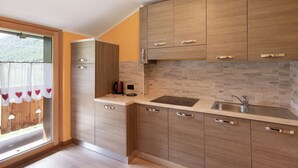A modern kitchen with wooden cabinets, a built-in sink, and a window with a view of the outdoors. - “Appartamento Legnameir Bait da Rez” with Balconies & Wi-Fi (Livigno)