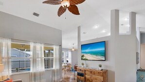 Un salon spacieux avec une grande télévision, des meubles en bois et une vue sur l’extérieur.