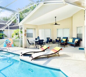 Un espace extérieur abrité avec une piscine, des chaises longues, une table et des chaises.