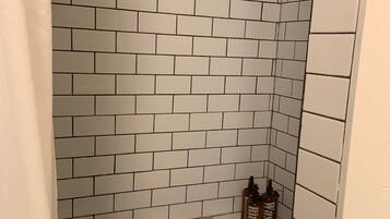 A bathroom with white subway tiles, a towel rack, and two bottles labeled "Rinse" on a shelf.