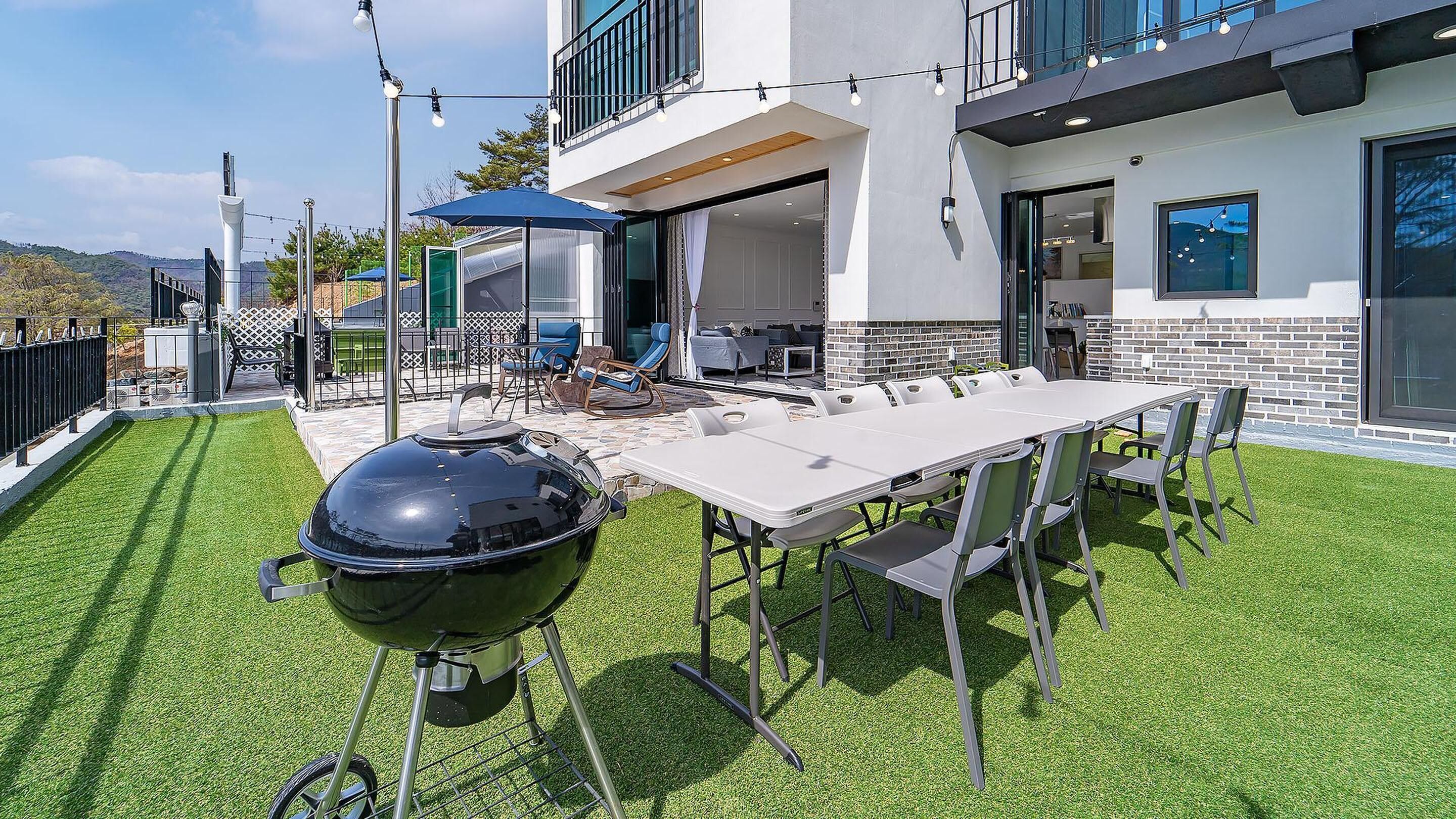 A modern outdoor patio with a barbecue grill, a dining table, and outdoor seating.