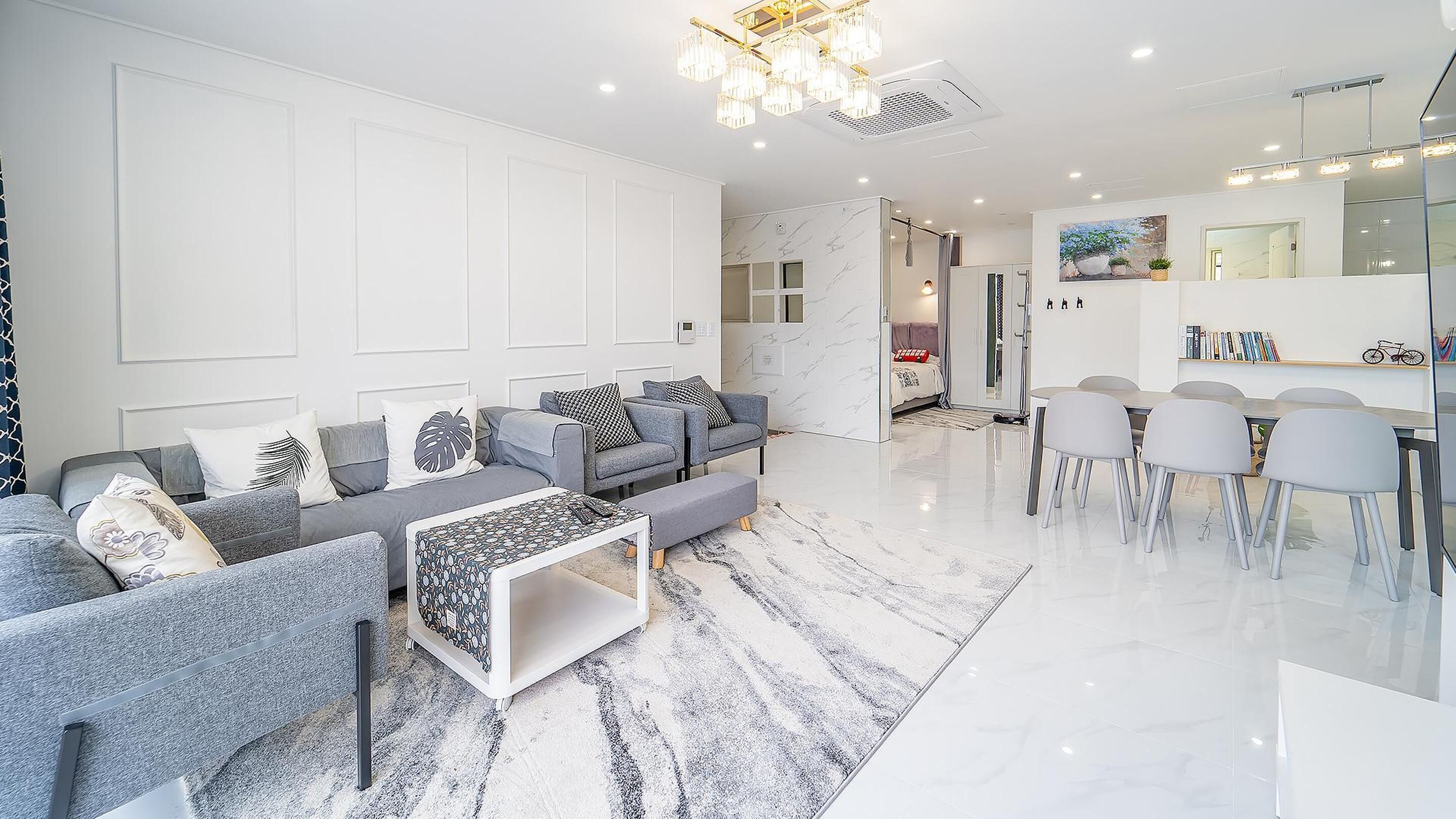 A modern living room with a sofa set, a coffee table, and a dining area with chairs.