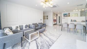 A modern living room with a sofa set, a coffee table, and a dining area with chairs.
