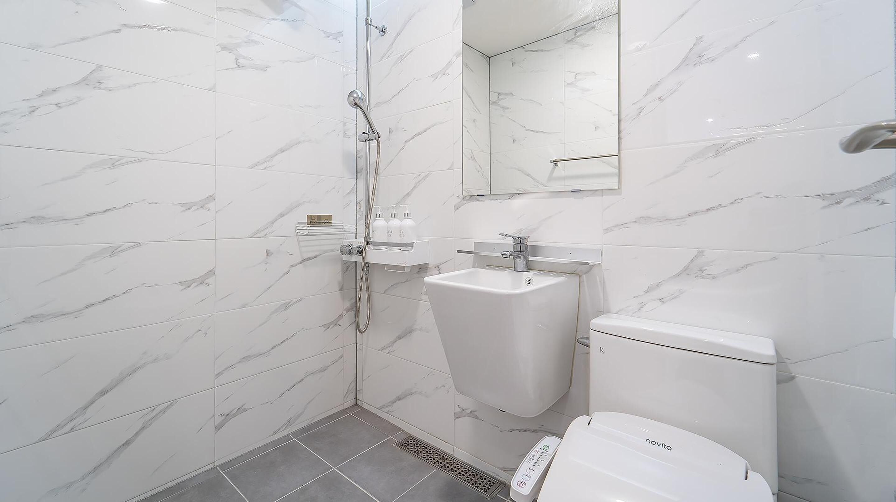 Un bany modern amb dutxa protegida per vidre, un lavabo pedestal i un vàter.