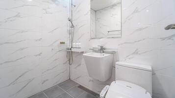 Un bany modern amb dutxa protegida per vidre, un lavabo pedestal i un vàter.