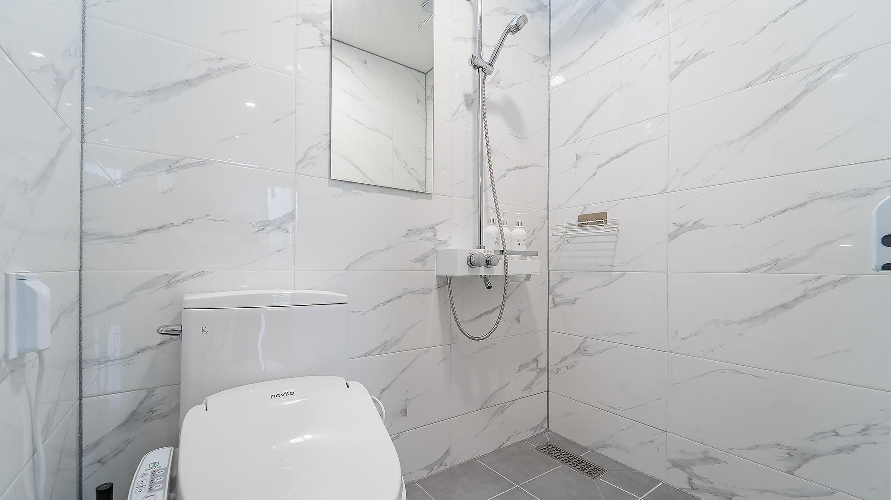 Een moderne badkamer met toilet, douche en spiegel.