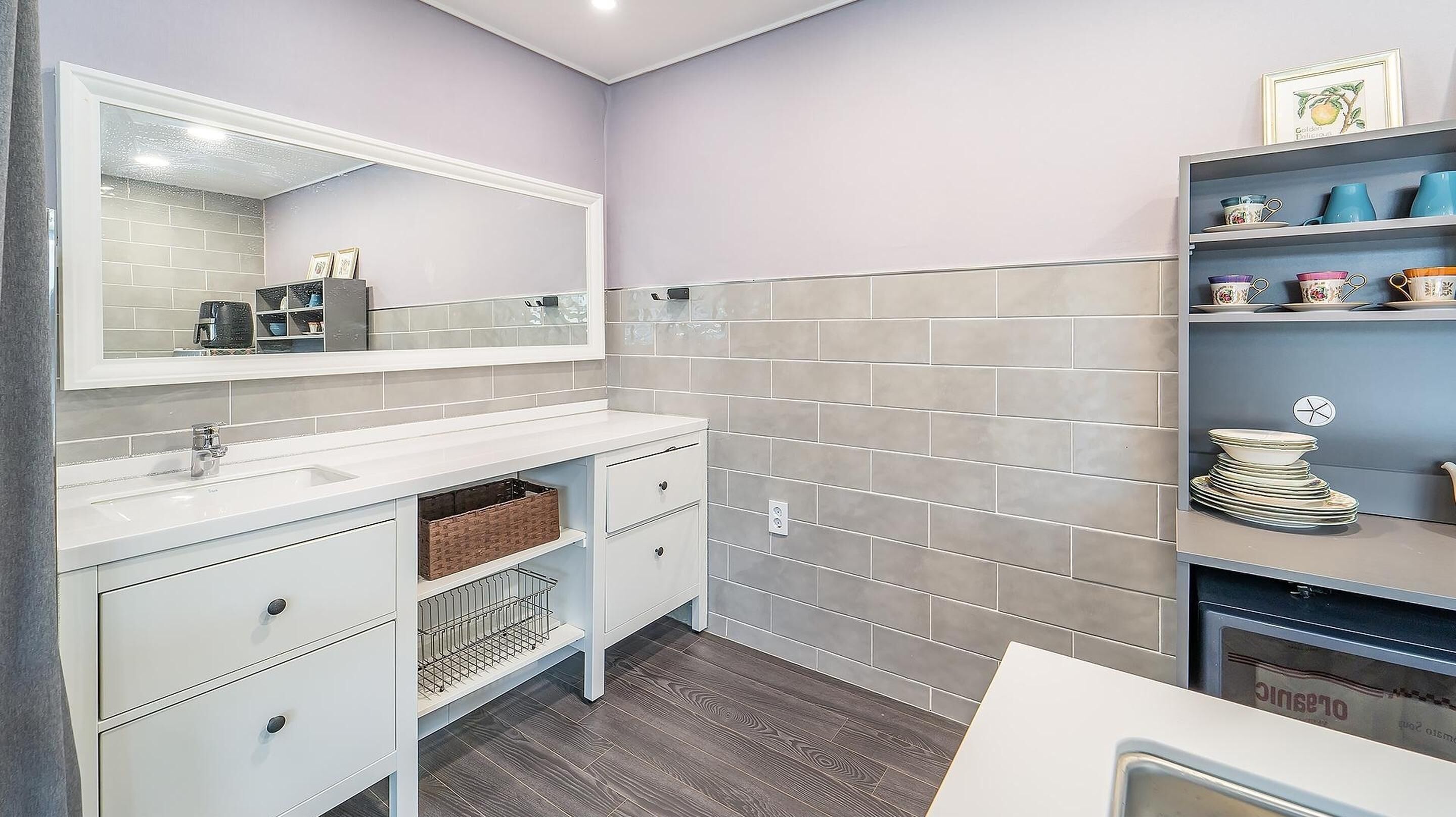 A bathroom with a white vanity, a large mirror, and a tiled backsplash.