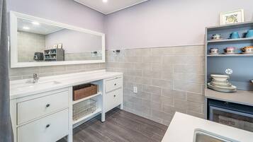 A bathroom with a white vanity, a large mirror, and a tiled backsplash.