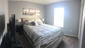 Un dormitorio con una cama, un televisor y una ventana.