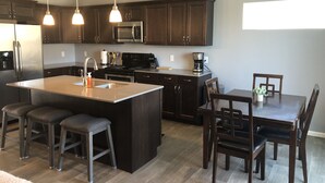 Una cocina moderna con armarios de madera oscura, electrodomésticos de acero inoxidable y una isla central con taburetes de bar.