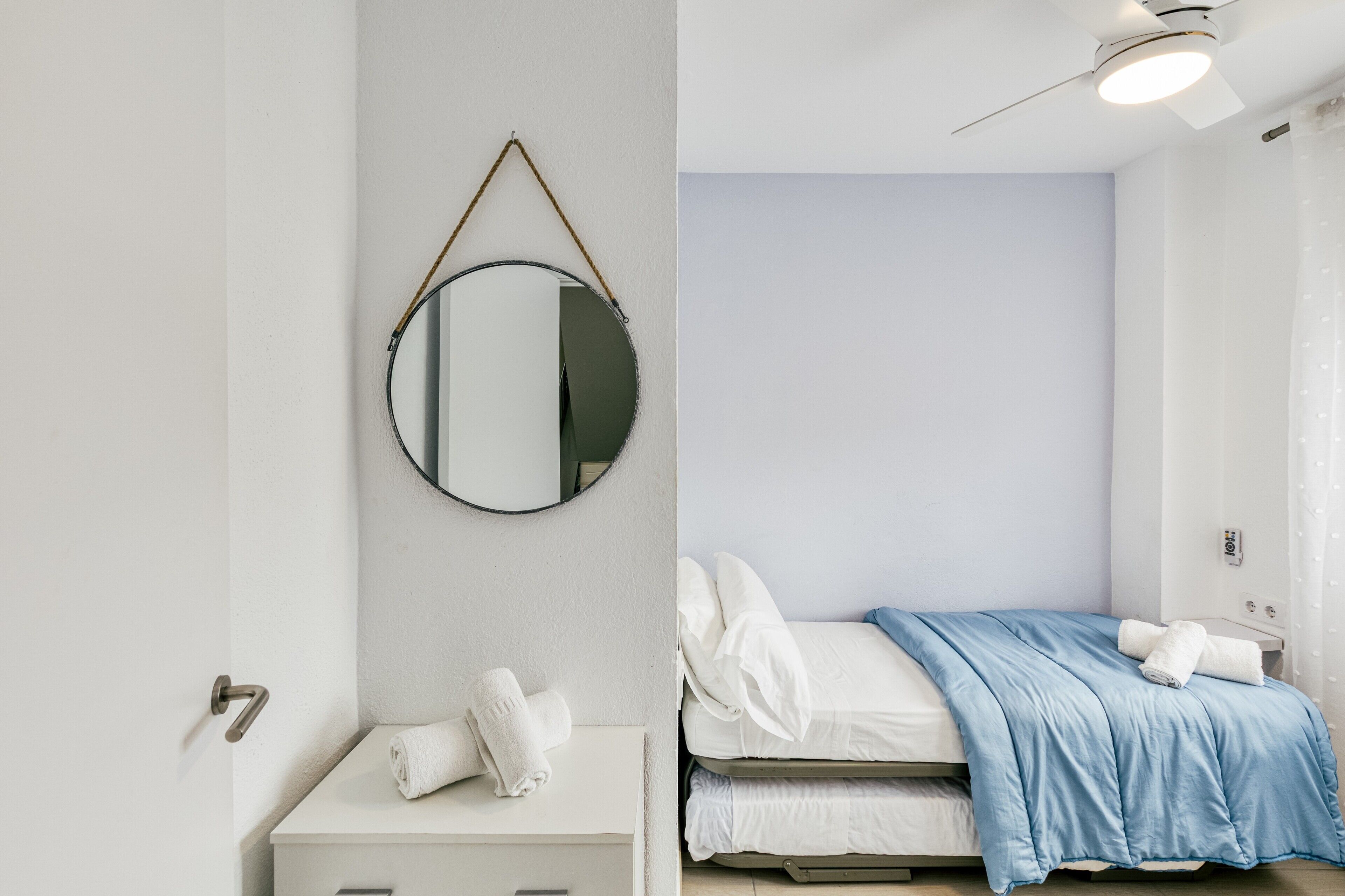 Una camera da letto con un letto, un comodino, uno specchio e una ventola a soffitto.