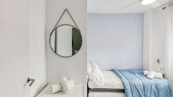Una camera da letto con un letto, un comodino, uno specchio e una ventola a soffitto.